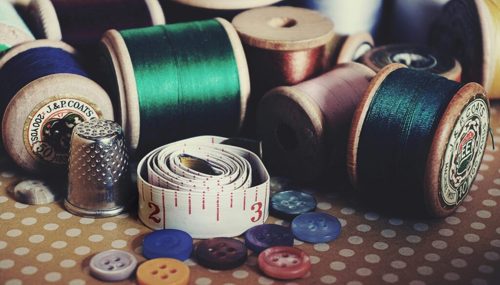 Close-up of vintage sewing essentials including threads, buttons, thimble, and measuring tape.