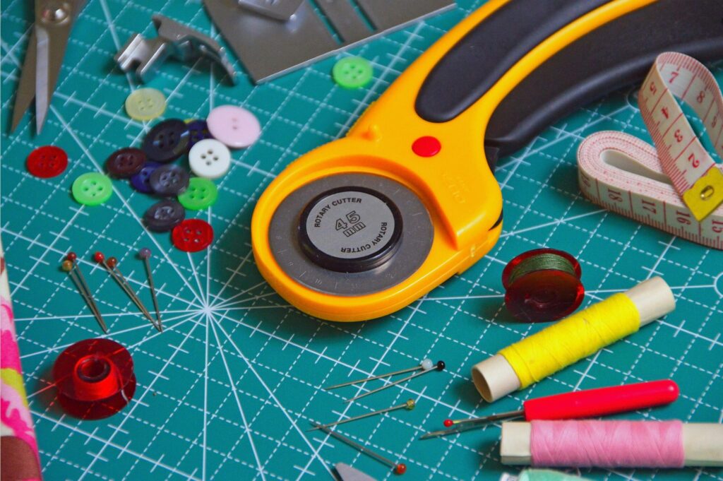 A vibrant collection of sewing tools including rotary cutter, threads, and buttons on a table.