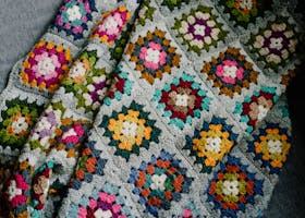 A vibrant handmade crochet blanket featuring geometric patterns in various colors.
