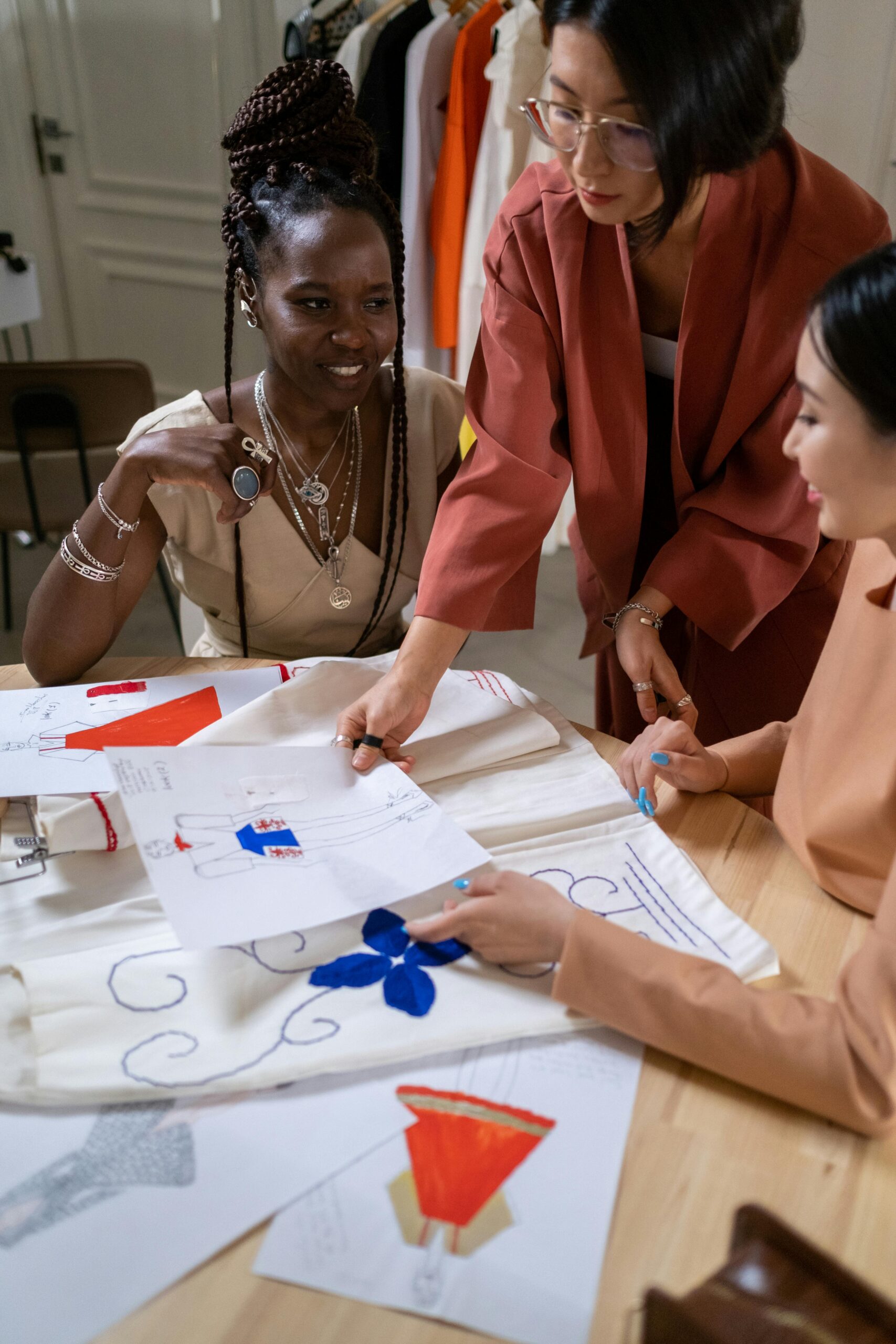 Diverse team of women collaborating on fashion designs in a studio setting.